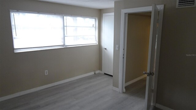 unfurnished bedroom featuring visible vents, baseboards, light wood-style floors, and a closet