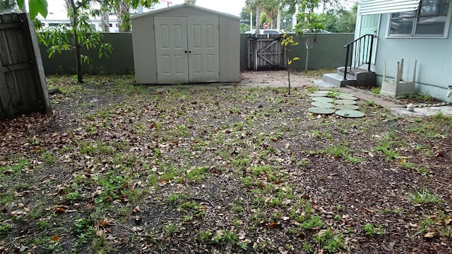 view of yard featuring an outbuilding, a fenced backyard, and a shed