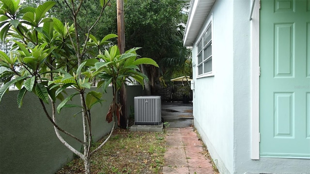 view of property exterior with stucco siding, central AC unit, and fence