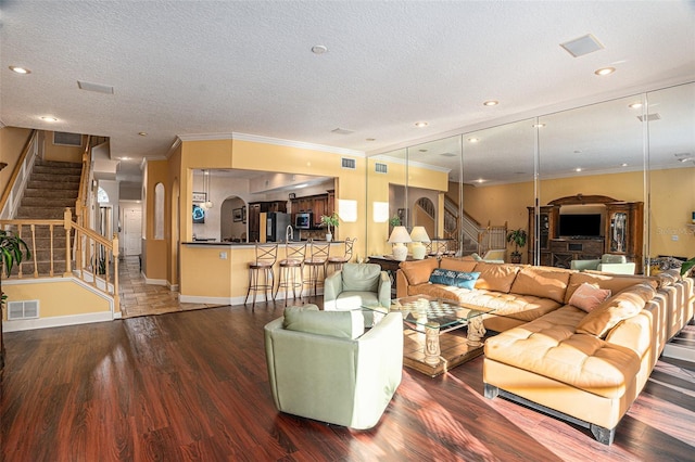 living room with a textured ceiling, crown molding, and dark hardwood / wood-style floors