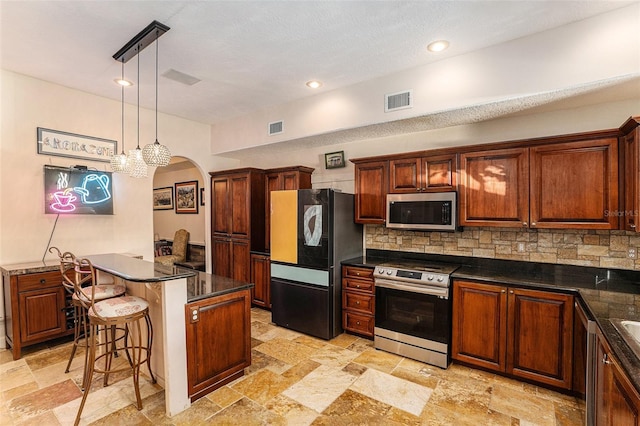 kitchen featuring hanging light fixtures, a center island, backsplash, appliances with stainless steel finishes, and a kitchen breakfast bar