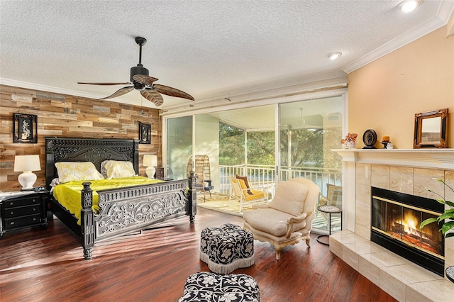 bedroom with a textured ceiling, ornamental molding, a fireplace, ceiling fan, and wood-type flooring