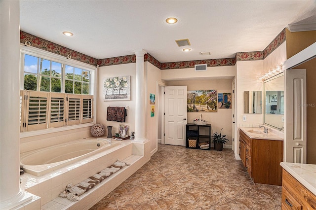 bathroom with a relaxing tiled tub, a textured ceiling, and vanity