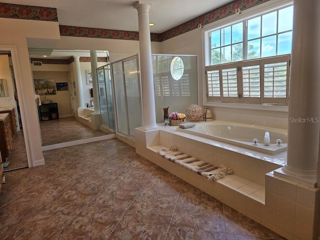 bathroom with a textured ceiling, separate shower and tub, and ornate columns