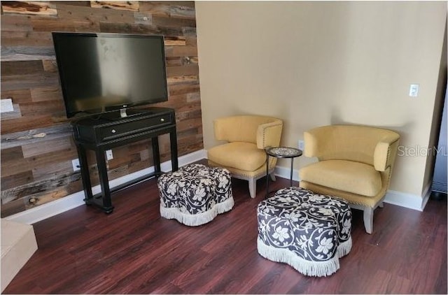 living area with wooden walls and dark hardwood / wood-style floors