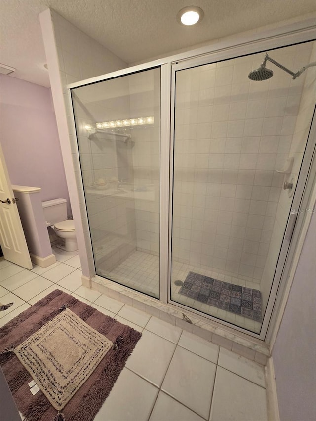 bathroom with a textured ceiling, a shower with door, tile patterned floors, and toilet