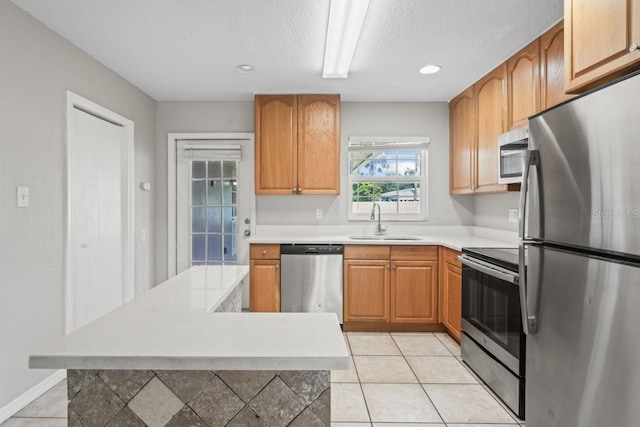 kitchen with light tile patterned flooring, appliances with stainless steel finishes, sink, and a textured ceiling