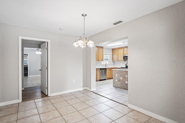 unfurnished dining area featuring light tile patterned flooring and ceiling fan with notable chandelier