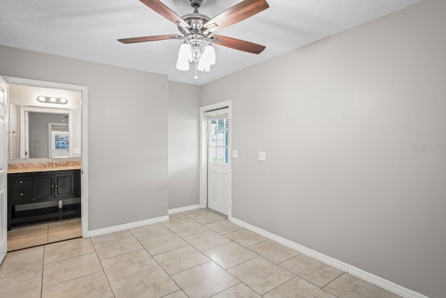 tiled empty room featuring ceiling fan and sink