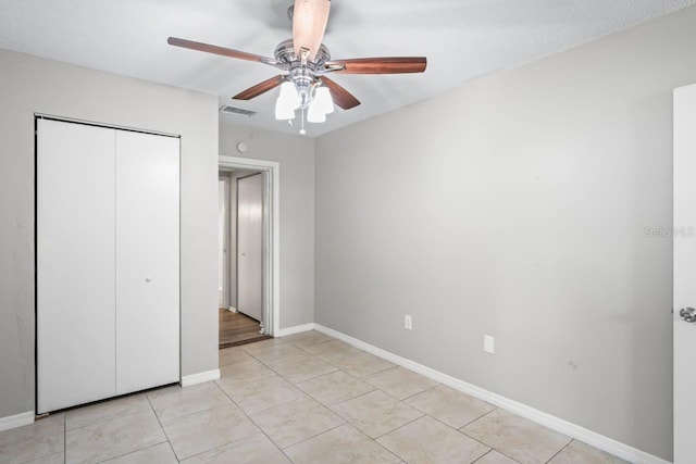 unfurnished bedroom featuring ceiling fan, a closet, and light tile patterned floors