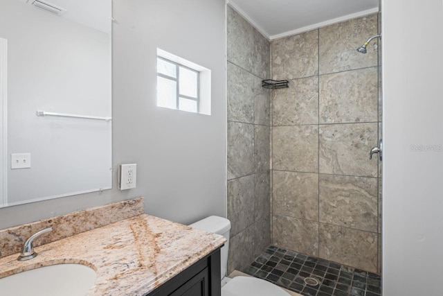 bathroom featuring vanity, toilet, and a tile shower