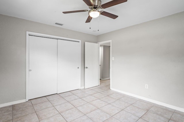 unfurnished bedroom with light tile patterned flooring, ceiling fan, and a closet