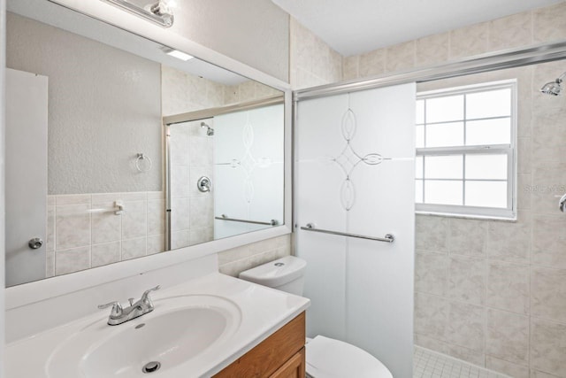 bathroom featuring vanity, a shower with door, and toilet