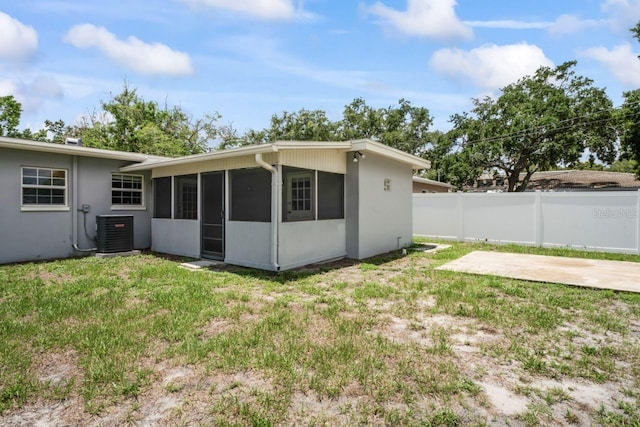 back of property with a yard, a sunroom, a patio, and central air condition unit