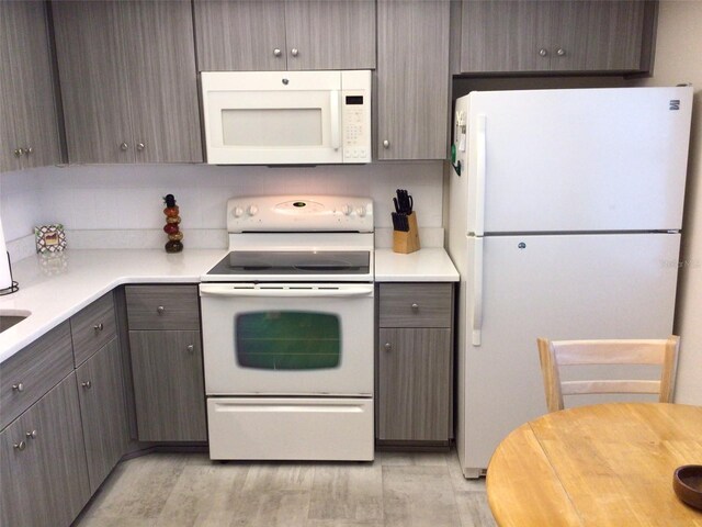 kitchen featuring light hardwood / wood-style flooring, dark brown cabinets, and white appliances