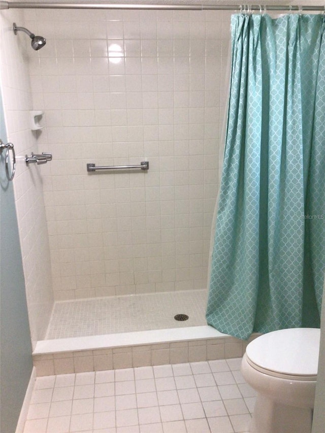 full bathroom featuring a stall shower, tile patterned flooring, and toilet