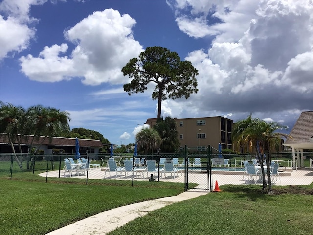 view of property's community with a yard, fence, and a pool