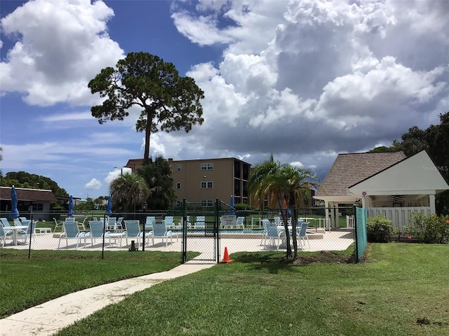 view of community with a lawn, fence, and a pool