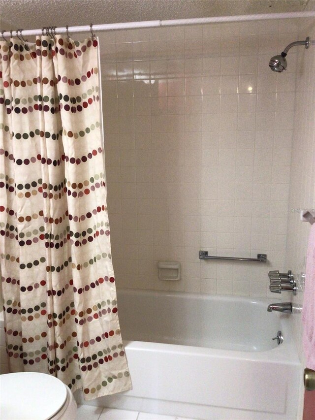 bathroom with tile patterned floors, shower / bath combo, and toilet