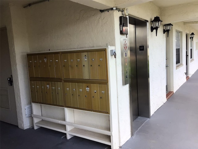 exterior space featuring a mail area, concrete flooring, and elevator