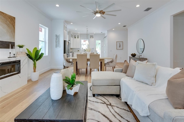 living room featuring light hardwood / wood-style floors, ornamental molding, and ceiling fan