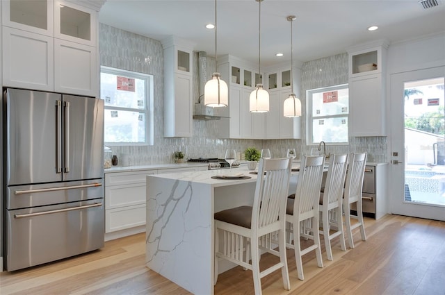 kitchen with light stone countertops, white cabinetry, a center island, and high end fridge