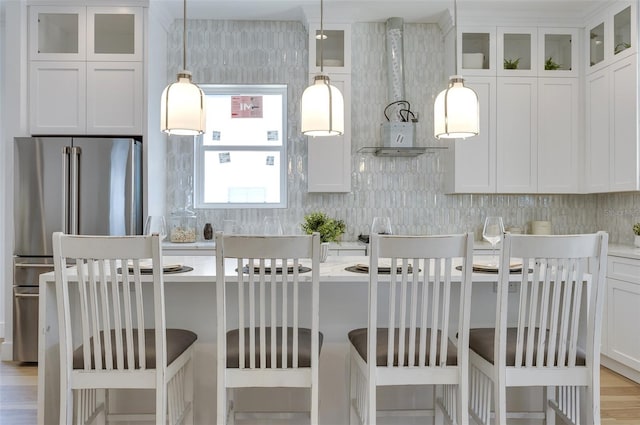 kitchen featuring decorative light fixtures, white cabinets, a breakfast bar area, and high end fridge