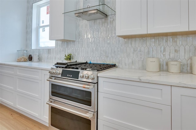 kitchen with extractor fan, backsplash, range with two ovens, and white cabinets