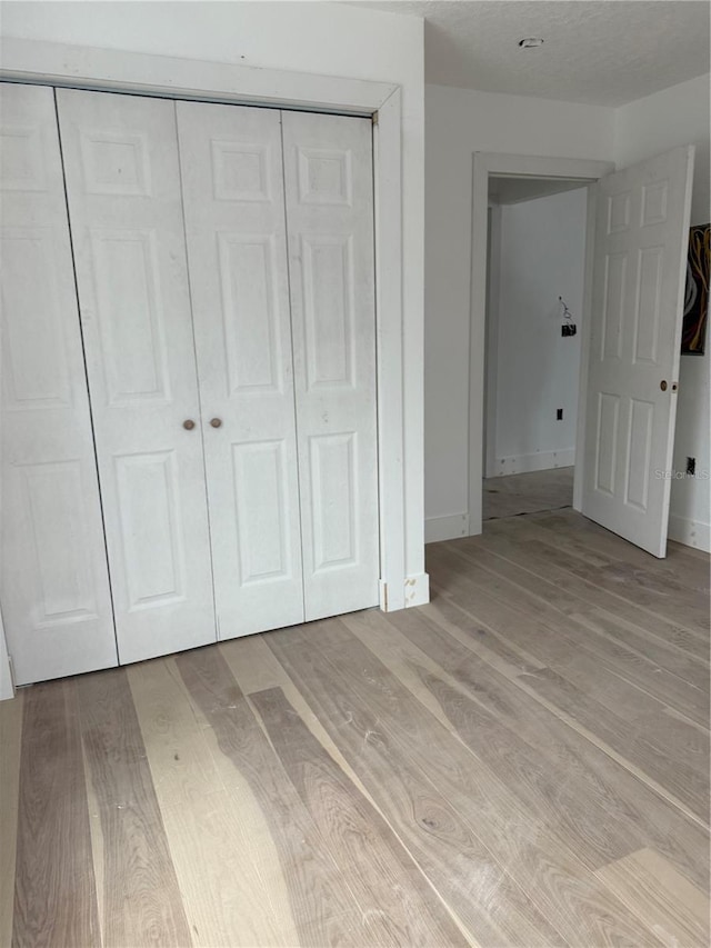 unfurnished bedroom featuring light hardwood / wood-style flooring and a closet