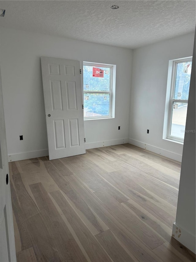 unfurnished room featuring a textured ceiling and light wood-type flooring