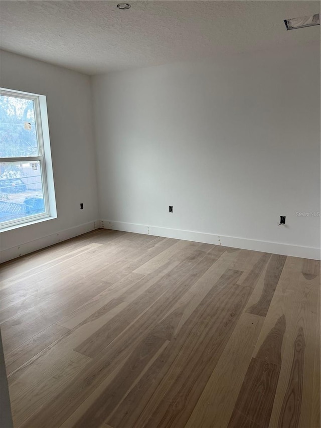 spare room featuring light hardwood / wood-style floors and a textured ceiling