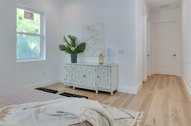 bedroom with baseboards, visible vents, and light wood finished floors