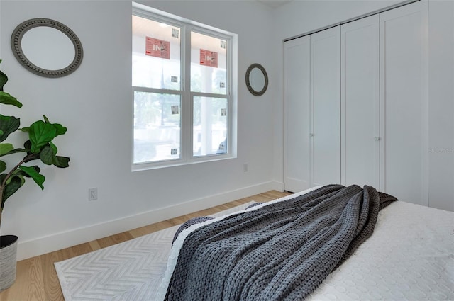 bedroom with light wood finished floors, baseboards, and a closet