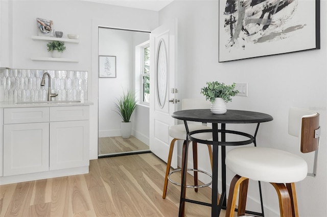 dining area with light wood-style floors, wet bar, and baseboards