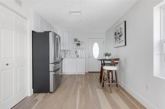 kitchen with visible vents, open shelves, freestanding refrigerator, and white cabinetry