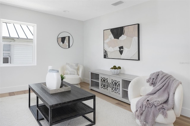 living area featuring baseboards, visible vents, and wood finished floors