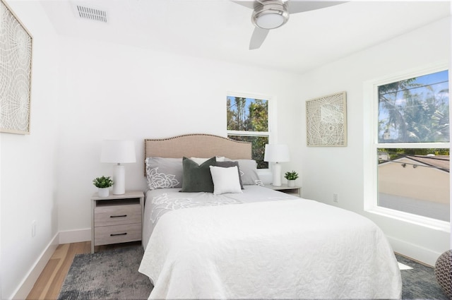 bedroom with baseboards, wood finished floors, visible vents, and a ceiling fan