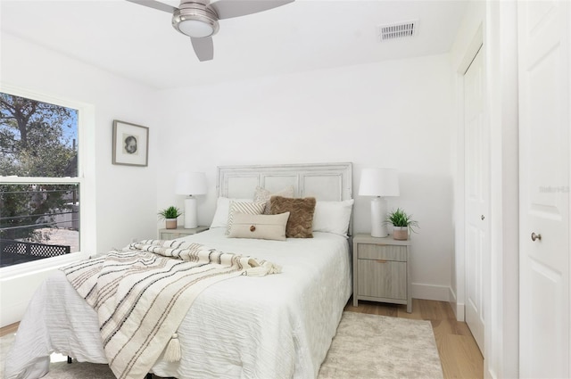 bedroom with multiple windows, wood finished floors, visible vents, and baseboards