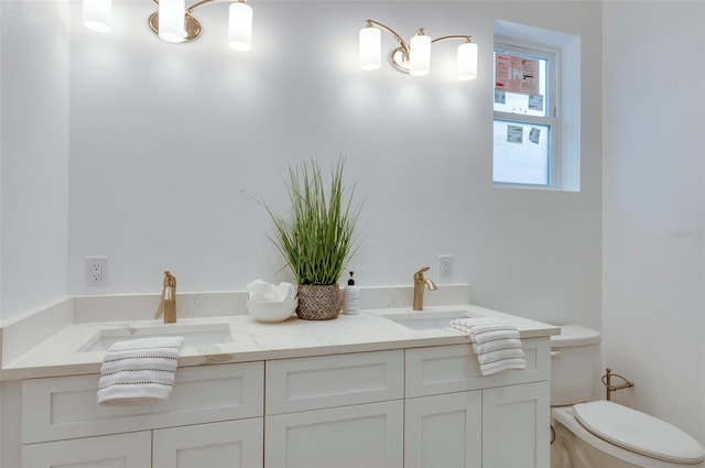 bathroom featuring double vanity, a sink, and toilet