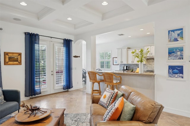 living room with beamed ceiling, plenty of natural light, light tile patterned floors, and coffered ceiling