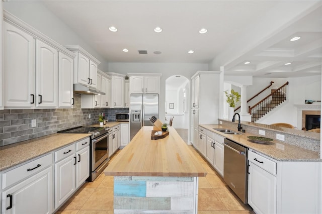 kitchen featuring white cabinetry, sink, stainless steel appliances, beamed ceiling, and kitchen peninsula