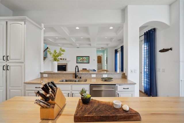 kitchen with beam ceiling, white cabinetry, sink, coffered ceiling, and stainless steel dishwasher