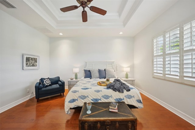 bedroom with a tray ceiling, ceiling fan, ornamental molding, and hardwood / wood-style flooring