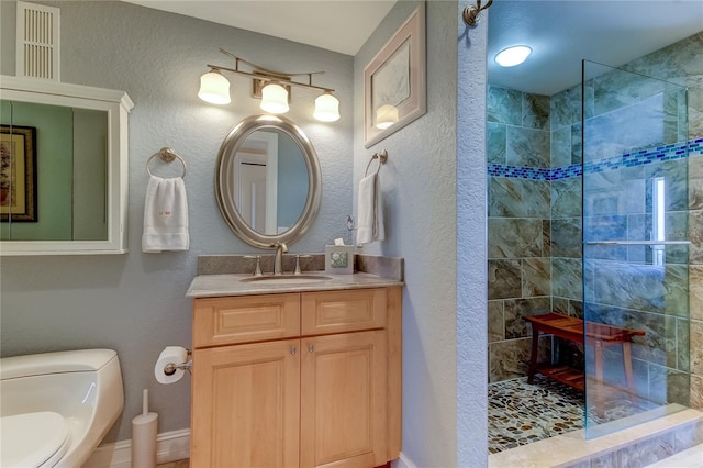 bathroom featuring a tile shower, vanity, and toilet