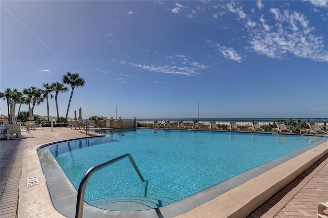 view of swimming pool featuring a water view and a patio