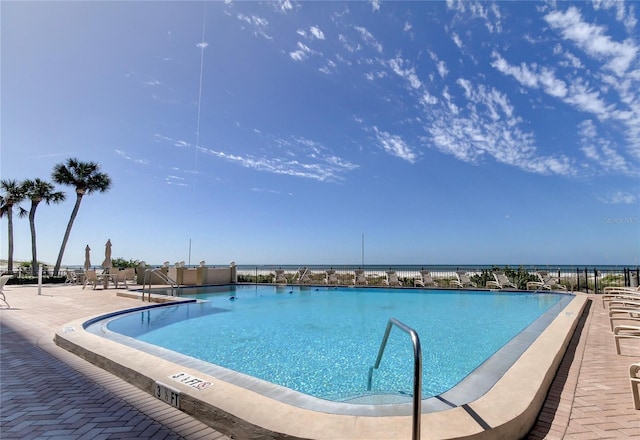 view of pool with a water view and a patio area