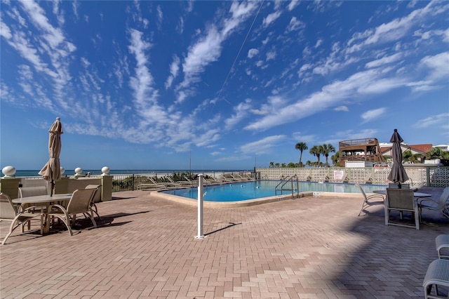 view of pool with a water view and a patio area