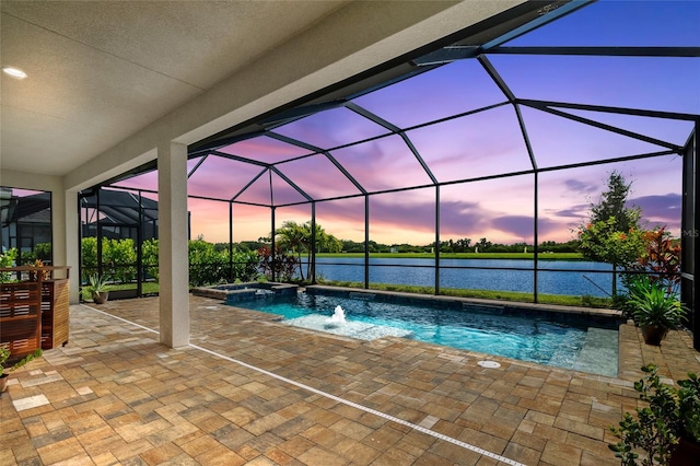 pool at dusk featuring an in ground hot tub, a water view, glass enclosure, and a patio