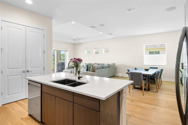 kitchen with sink, dishwasher, refrigerator, an island with sink, and light wood-type flooring