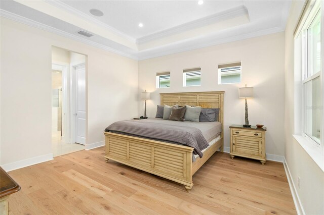 bedroom with a tray ceiling, light hardwood / wood-style flooring, and ornamental molding